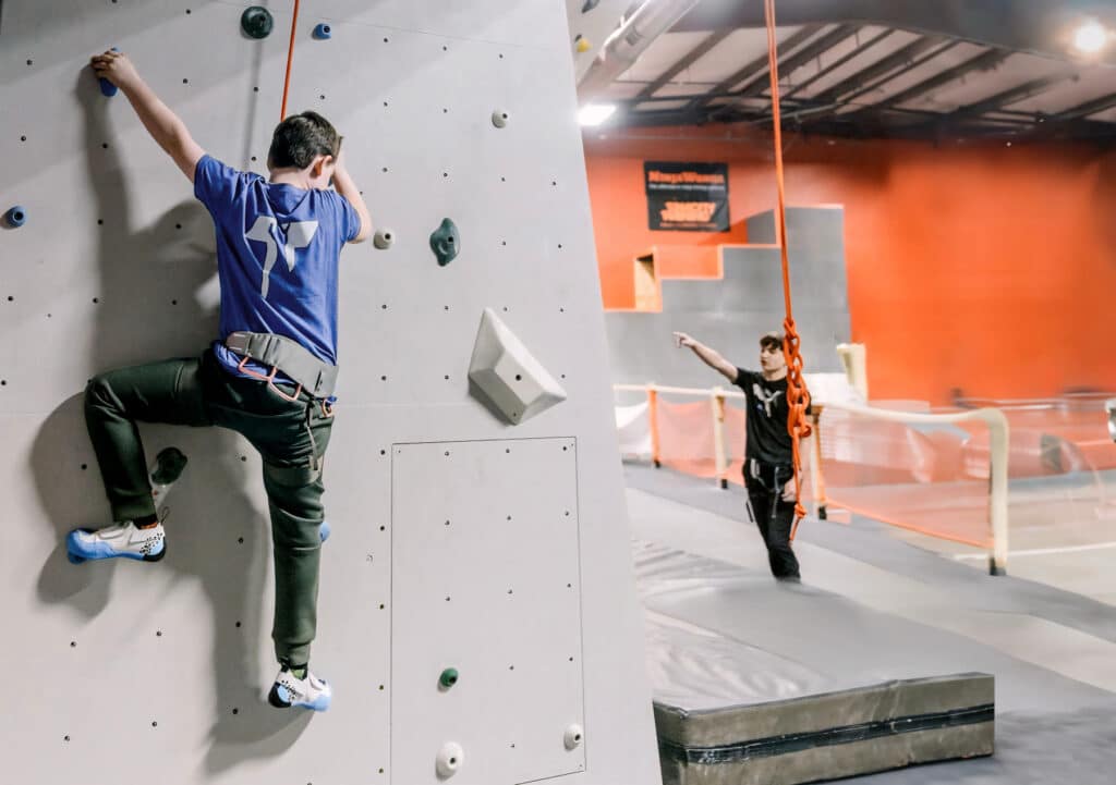 A climber tackling a rock wall in an indoor gym, focused and ready to conquer the challenge ahead.